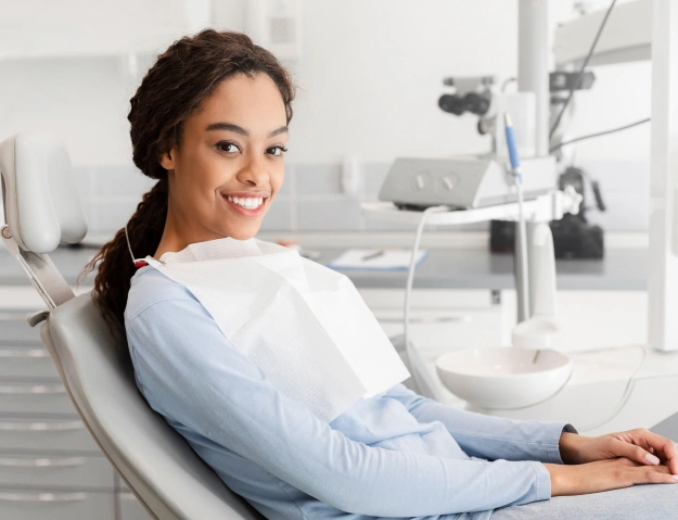 Woman smiling in dental chair at modern dentistry office during examination.