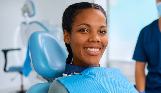 Smiling woman in dental chair wearing blue bib at family dentistry office