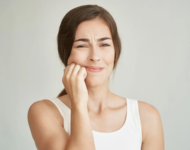 Woman touching face smiling against neutral background, dental care concept