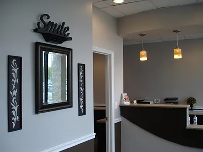 Modern dental office reception area with "Smile" sign, mirror, and front desk counter