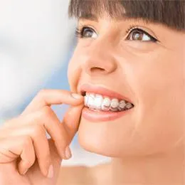 Young woman smiling while flossing teeth against blue and white background.