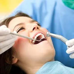 Child receiving dental examination with dentist using suction tool in dental office setting.
