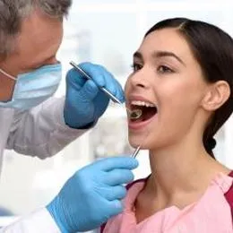 Dentist examining patient's teeth with tools during routine dental checkup appointment
