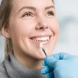 Woman receiving dental examination from dentist wearing blue gloves in clinical setting.